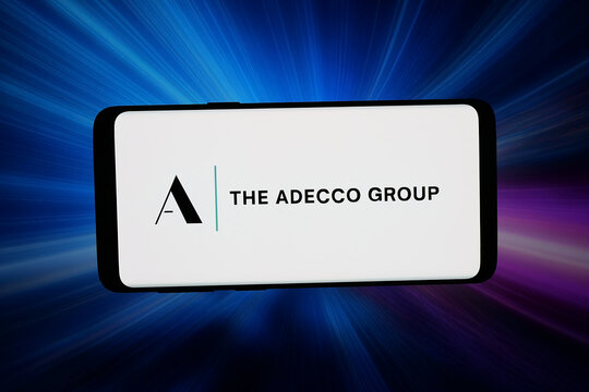 Stuttgart, Germany - 03-13-2026: In this photo illustration, the logo of HR and staffing company The Adecco Group is displayed on a smartphone in front of abstract background on computer screen.