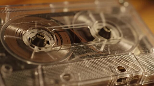 Video of Retro compact cassette reels turning in macro detail highlighting analog sound recording heritage, classic mixtape era and vintage entertainment aesthetic for editorial and promotional use.