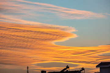 Dramatic sunset sky over Mediterranean coast with orange and yellow cirrus clouds. Beautiful evening atmosphere with soft light reflecting on colorful cloudscape. Antalya, Turkey.