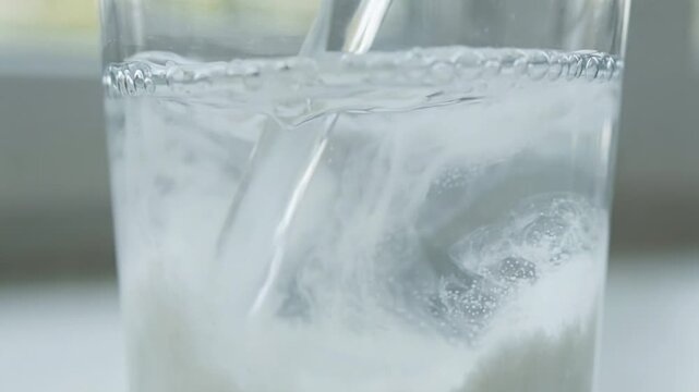A glass of water with a spoon in it