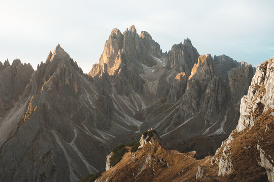 View of jagged peaks rise majestically against the soft sky, their rugged textures bathed in the warm glow of sunlight, a timeless scene, Auronzo di Cadore, Veneto, Italy.