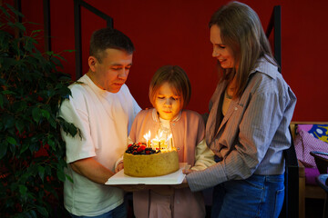 Family celebrates birthday with cake and candles in cozy setting