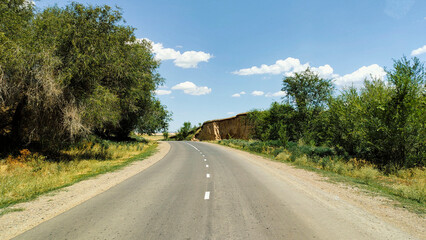 Naklejka premium Asphalt road for cars among mountains and green trees in summer.