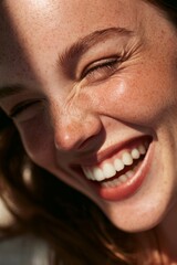 Fototapeta premium Extreme close up portrait of a woman with freckles laughing with genuine joy and white teeth