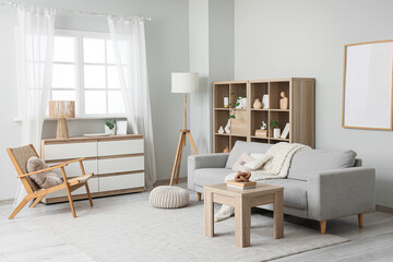 Interior of stylish living room with grey sofa, armchair and commode