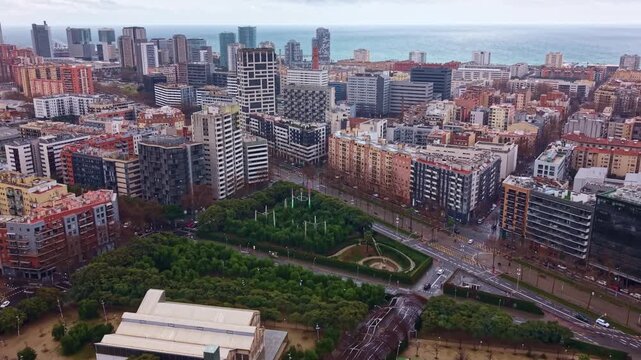 Parc del Centre del Poblenou and modern architecture along Avinguda Diagonal in Barcelona, Spain. Aerial drone forward