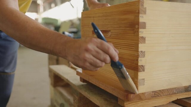 Man painting wooden box in workshop with focus on craft and detail