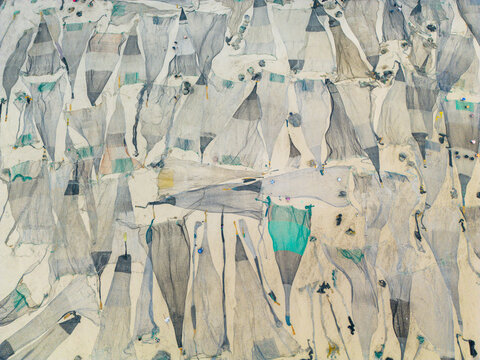 Aerial view of fishing nets laid out in the sun, creating a textured landscape of whites, grays, and subtle blues, Cox's Bazar, Chittagong Division, Bangladesh.