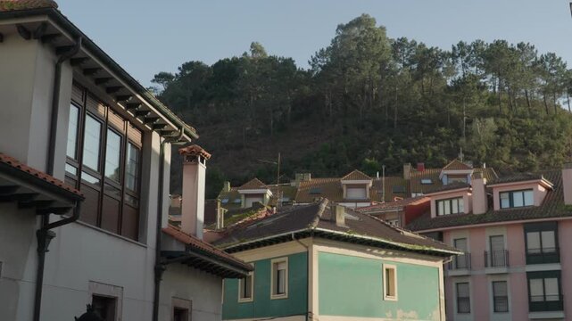 Traditional colorful houses built along a hillside in Cand&aacute;s, Asturias, Spain. Residential neighborhood surrounded by green forest creating a peaceful coastal town atmosphere in northern Spain.
