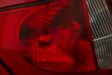 Closeup red car tail light glossy reflection. Close-up of a red rear car light, highlighting modern vehicle design © Alena