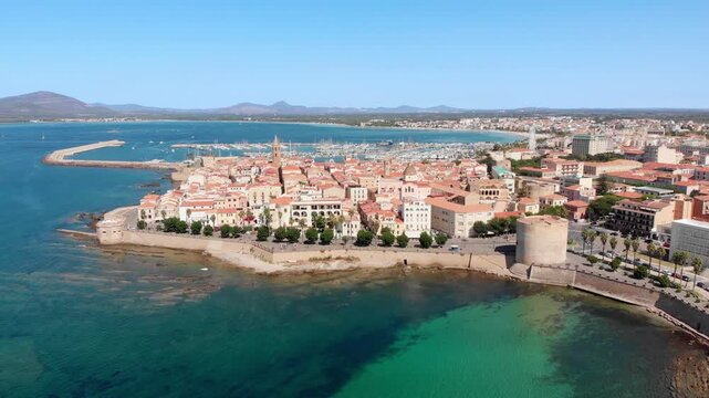 Aerial drone approaching Alghero old town along the Mediterranean coastline.