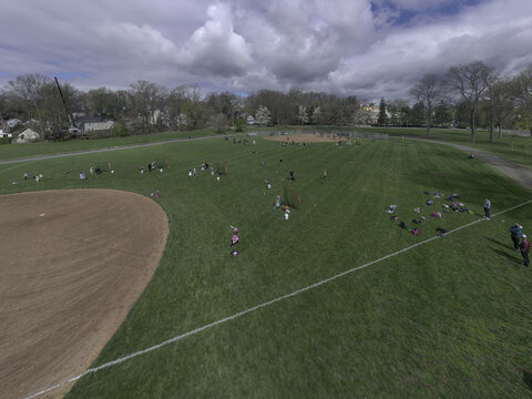 Aerial view of a vibrant green field dotted with colorful objects and people enjoying a sunny day near the baseball field, Summit, New Jersey, United States.
