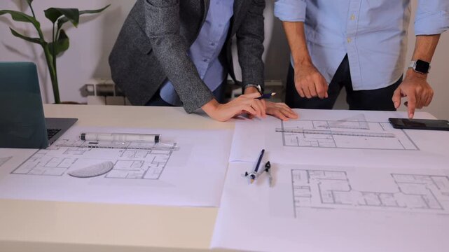 Professional architects collaborating on building blueprint design, engineers drawing and discussing technical details of a new construction project in modern office