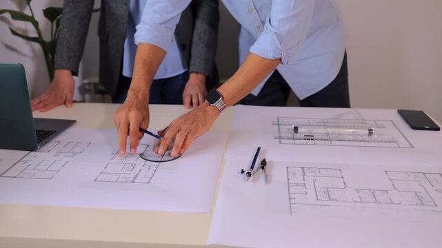 Professional architects designing a house blueprint. Engineers collaborating in the office. Team working on a construction project, drawing with a pencil and protractor