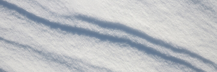 Beautiful winter background with snowy ground. Natural snow texture. Wind sculpted patterns on snow surface. Wide panoramic texture for background and design. © Andrei Stepanov