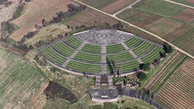 Aerial view of the French Military Cemetery, a solemn landscape with rows of graves amidst green grass and stone pathways, Mittelwihr, Grand Est, France.