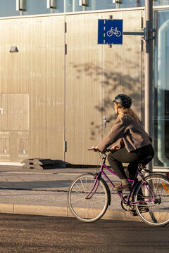 Street bike lane in Oslo Norway with woman cyclist riding in daylight during autumn showing commute mobility lifestyle and urban transportation