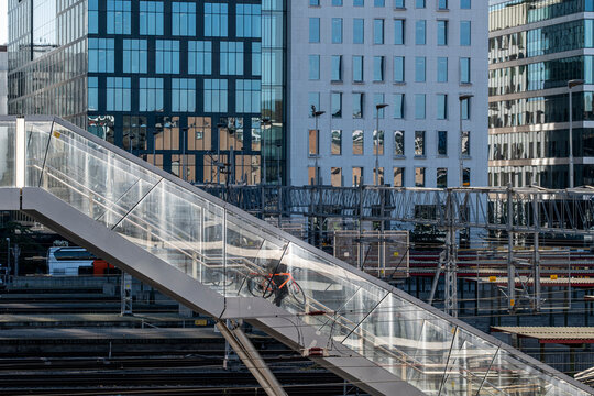 Urban Oslo Norway bridge commute with cyclist crossing above railway tracks in daylight during autumn showing city architecture and transit lines