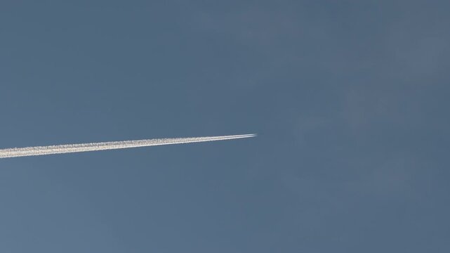 Jet aircraft crossing sky with visible contrail