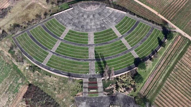 Aerial view of the War Cemetery, a somber yet serene landscape of green grass, grey stone, and neat rows, creating a place for reflection, Mittelwihr, Grand Est, France.