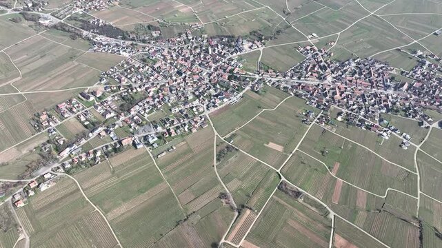 Aerial view of the village, a blend of red-roofed buildings nestled amid a patchwork of vineyards and fields, Mittelwihr, Grand Est, France.