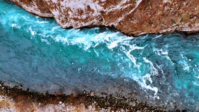 Top down view of turquoise river rapids and rocks. Aerial nadir shot of rushing turquoise water flowing against rocky canyon walls in Montenegro.