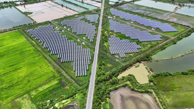 High-angle drone footage capturing large solar panel arrays beside a rural road and farmland, illustrating clean energy production, sustainable infrastructure, and modern renewable power generation