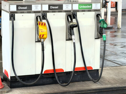 Fuel pumps on a petrol station forecourt showing petrol and diesel nozzles with one deisel pump showing gas is empty. 