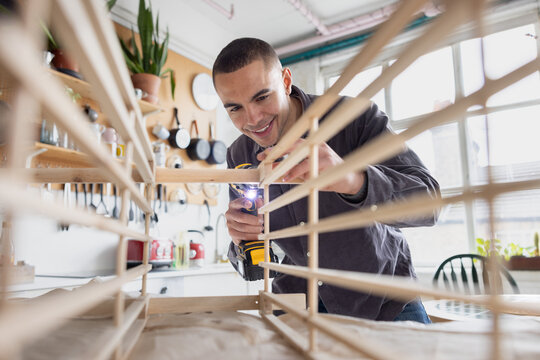 Young Happy Man putting together a piece of flatpack furniture