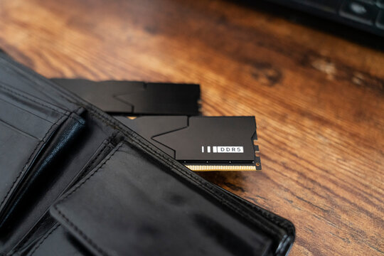Black DDR5 RAM memory modules placed inside a black wallet on wooden surface. RAM shortages on the market, rising prices, and increased demand driven by the growing need for AI training.