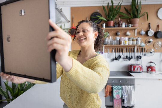 Smiling Woman ready to hang a picture in her new home