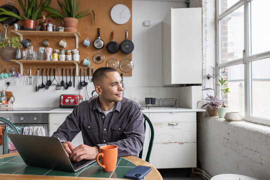 Young man planning his future working on a laptop in a kitchen