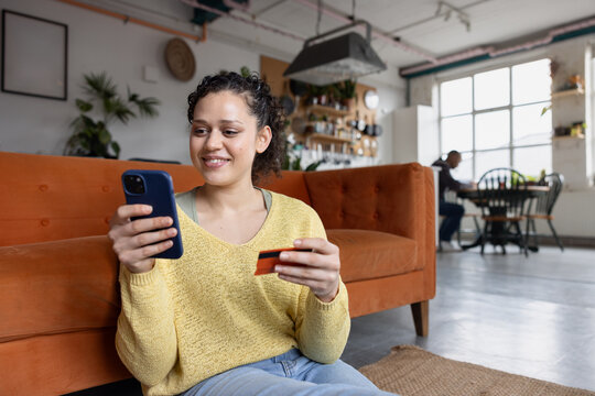 Young adult woman at home shopping on smartphone mobile