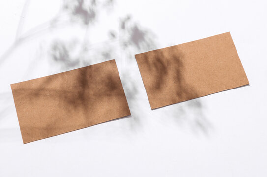 Cardbord brown business cards with shadow from sunlight on a white background