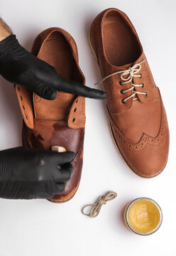 Shoemaker applies shoe polish to leather shoes on a white background