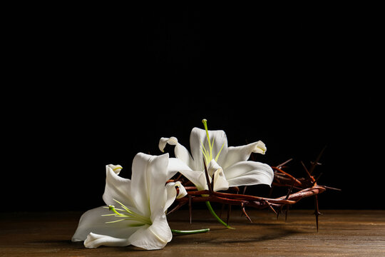 Crown of thorns with beautiful lily flowers on wooden table