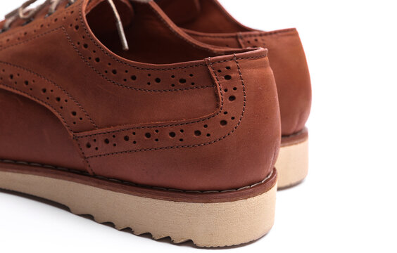 Brown leather brogue boots on white background.