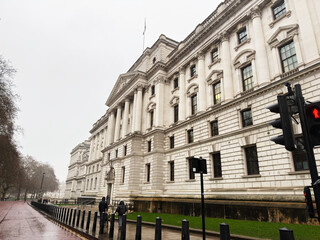 Naklejka premium London government building with classical columns along a wet street near traffic light