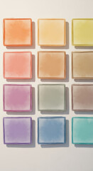 Fototapeta premium Twelve translucent, rectangular blocks displaying soft gradient colors are neatly organized in a three-by-four grid against a light surface.