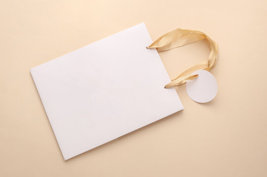 Mockup of white premium cardboard bag with tag on a beige background