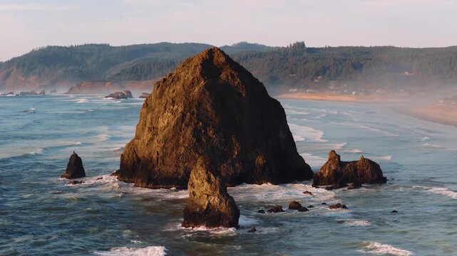 Drone footage of Cannon Beach at sunset with Haystack Rock and sandy shoreline. Excellent for nature, landscape, or scenic projects.
