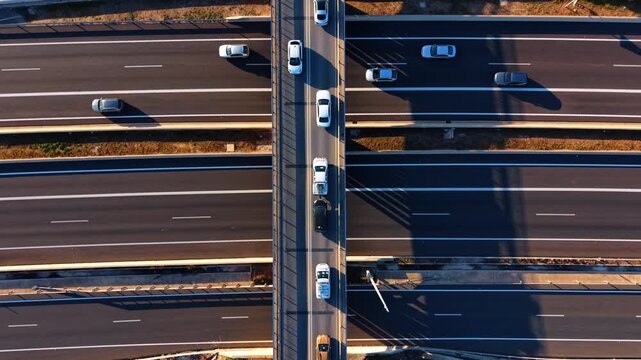 Aerial view of traffic on highway and bridge. Top down perspective of vehicles moving on different levels of road infrastructure.