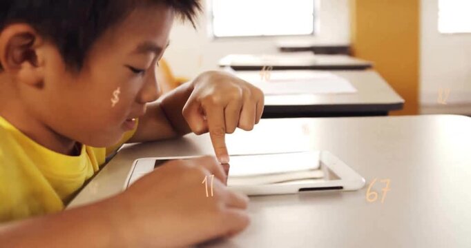 Animation of multiple numbers over close of smiling asian boy using digital tablet in classroom