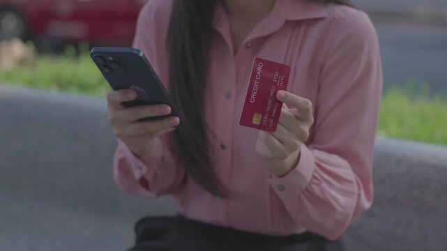 Close-up of a woman holding a credit card and smartphone, making an online payment or shopping on a mobile app, representing digital finance, e-commerce, and modern cashless transactions.