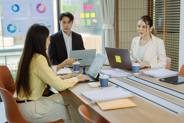 Obraz premium A business group meeting is underway, discussing charts and graphs that illustrate the results of successful teamwork among Asians.