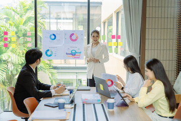 Fototapeta premium A business group meeting is underway, discussing charts and graphs that illustrate the results of successful teamwork among Asians.