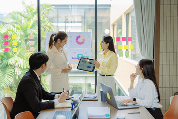 Fototapeta premium A business group meeting is underway, discussing charts and graphs that illustrate the results of successful teamwork among Asians.