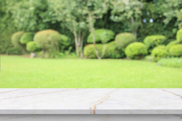 Naklejka premium Empty marble table top with abstract blur green park garden background