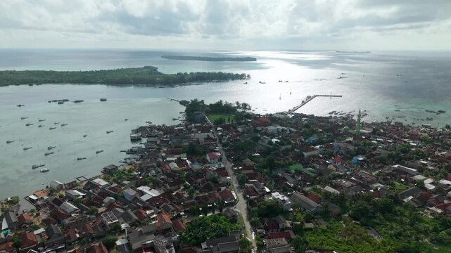 Aerial view of the Karimunjawa Town Square with houses, boats, and a pier extending into the ocean, Karimunjawa, Central Java, Indonesia.
