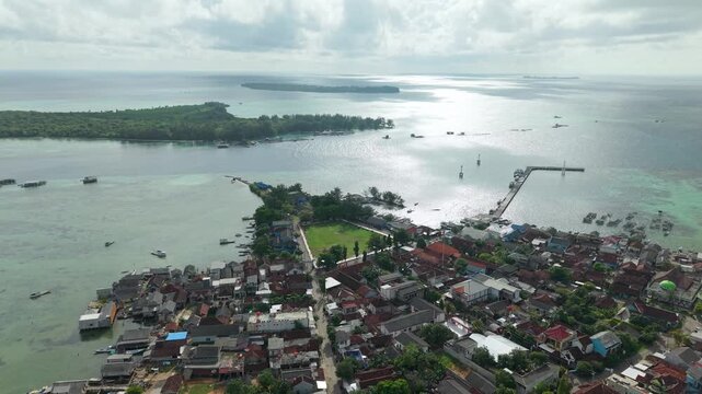 Aerial view of Karimunjawa Town Square showing the pier and boats along the coast, a mosque and the vast ocean, Karimunjawa, Central Java, Indonesia.
